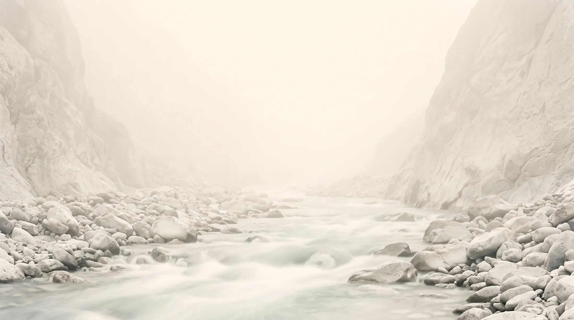 A river running out of a mountain valley, the slopes lost in fog.